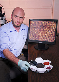 Georgia Tech researcher Jason Nadler poses with materials used to form copper structures that are precursors to explosive compounds. The materials, formed on chips, are being used to improve detonators used by the U.S. Navy.
