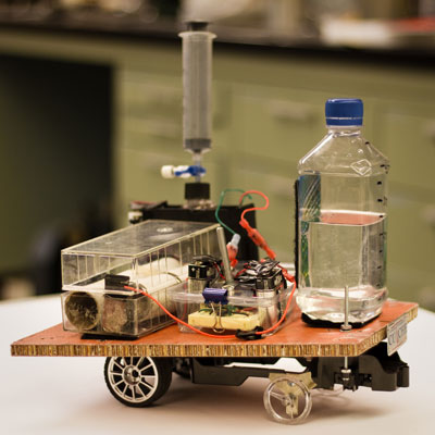 The ChemE car, Zoidberg. On the left are the two batteries; in the middle is the circuitry that detects the iodine clock reaction; on the right is the water load required in the competition; and behind everything is the "black box" where the iodine clock reaction occurs. Provided/Woojin Kim