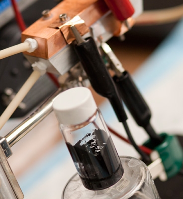 A sample of 'Cambridge crude'  a black, gooey substance that can power a highly efficient new type of battery. A prototype of the semi-solid flow battery is seen behind the flask.
Photo: Dominick Reuter