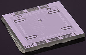 NIST's "optics table on a chip" is a superconducting circuit on a square sapphire chip about 6 millimeters wide. Scientists use the chip to place a single microwave photon in two frequencies, or colors, at the same time. The photon is prepared by an "artificial atom" (small yellow square) in the middle of the chip. The arrow shape at the lower left connects to a transmission line used to tune the SQUID (small black area near the point of the arrow). The SQUID couples together two resonant frequencies of the cavity (meandering line), and the photon oscillates between different superpositions of those frequencies.
Credit: D. Schmidt/NIST
