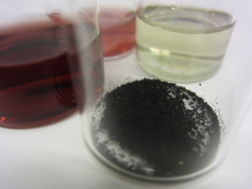 Researchers have combined gold nanoparticles (in light red) with copper nanoparticles (in light green) to form hybrid nanoparticles (dark red), which they turned into powder (foreground) to catalyze carbon dioxide reduction. 