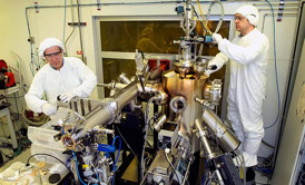 Inside a clean room, Brookhaven physicists Ivan Bozovic (left) and Anthony Bollinger work on the molecular beam epitaxy system that produced the atomically perfect materials used in the study.