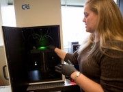 Postdoc Nicole Iverson demonstrates the instrument used to measure the fluorescent signal from nanotube sensors that detect nitric oxide. Photo: Bryce Vickmark