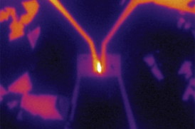 In the team's experimental setup, electricity was supplied to a tiny piece of tungsten selenide (small rectangle at center) through two gold wires (from top left and right), causing it to emit light (bright area at center), demonstrating its potential as an LED material. 
IMAGE COURTESY OF BRITT BAUGHER AND HUGH CHURCHILL