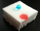 Demonstration of the oleophilic and at the same time hydrophobic properties of a silylated nanocellulose sponge: A droplet of water (blue) sits on the surface, whereas a droplet of oil (red) is absorbed by the material.
Image: Empa