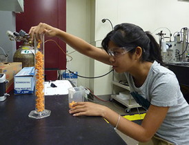 High school student Jessica Young checking the packing density of random aggregates of plastic spheres in a cylinder. Young's work as a summer intern at NIST contributed to a paper arguing that rigid aggregates like those she's testing tend to clump together at roughly the same density regardless of scale, from microscopic soot to large comets.
Credit: Baum/NIST