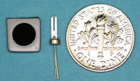 Vahala's new laser frequency reference (left) is a small 6 mm disk; the quartz "tuning fork" (middle) is the frequency reference commonly used today in wristwatches to set the second. The dime (right) is for scale.
Credit: Jiang Li/Caltech