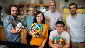 Doctoral student Melik Turker, left, holds a model of a dodecahedron in the lab of Ulrich Wiesner. Also pictured are doctoral student Yunye Gong, center, holding a model of a cage structure, and postdoctoral researcher Kai Ma, holding an icosahedron. The group's paper on their discovery of nanoscale 12-sided silicon cage structures published recently in Nature; in the back row, left-to-right, are Wiesner, engineering professor Peter Doerschuk and postdoc Tangi Aubert.
