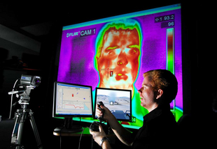 COGNITION RESEARCHER ROB ABBOTT

Sandia researcher Rob Abbott uses a joystick and plays the role of a student in a training exercise driving an amphibious assault vehicle simulator used by the Navy and Marines. The second monitor is an instructor/operator application called CDMTS. In the background is a thermal image of a student's face used for investigating biometrics to monitor the student in various ways including the level of engagement and focus of attention. (Photo by Randy Montoya)