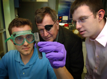 Purdue researchers demonstrate their method for producing hydrogen by adding water to an alloy of aluminum and gallium. The hydrogen could then be used to run an internal combustion engine or a fuel cell. The reaction was discovered by Jerry Woodall, center, a distinguished professor of electrical and computer engineering. Charles Allen, holding test tube, and Jeffrey Ziebarth, both doctoral students in the School of Electrical and Computer Engineering, are working with Woodall to perfect the process. (Purdue News Service file photo/David Umberger)