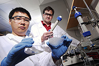 Researchers Kurt Pennell (standing) and Younggang Wang examine glass microbeads and sand used to study the transport and retention of C60 particles in water. (Georgia Tech Photo: Gary Meek)
