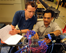 Researchers at Purdue are developing a miniature refrigeration system small enough to fit inside laptops and personal computers, a cooling technology that would boost performance while shrinking the size of computers. The researchers collect data using a myriad of sensors to precisely measure how a refrigerant boils and vaporizes inside tiny "microchannels" in a part of the refrigeration system called an evaporator. Data are needed to determine how to vary this boiling rate for maximum chip cooling. Eckhard Groll, at left, a professor of mechanical engineering, and Suresh Garimella, the R. Eugene and Susie E. Goodson Professor of Mechanical Engineering, discuss the microchannel data at the Ray W. Herrick Laboratories. (Purdue News Service photo/David Umberger)

