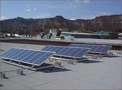 Solar power collectors, like these photovoltaic panels on a New Mexico high school roof, could be installed much more widely if they could be manufactured from less-costly materials. (U.S. Department of Energy photo)