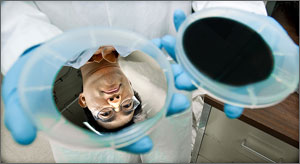 A silver wafer reflects the face of NREL research scientist Hao-Chih Yuan, before the wafer is washed with a mix of acids. The acids etch holes, absorbing light and turning the wafer black. Credit: Dennis Schroeder
