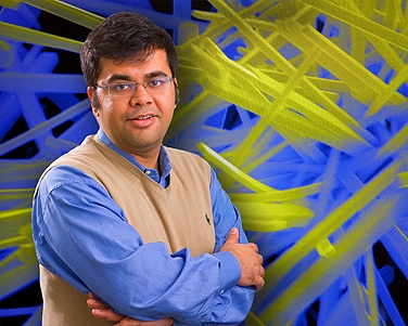 Sarbajit Banerjee stands in front of a scanning electron microscopy image of tungsten-doped vanadium-oxide nanowires, which have a phase transition temperature close to room temperature. Photo: DOUGLAS LEVERE