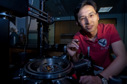 Rice University graduate student Jun Yao holds a memory chip made of silicon oxide. This chip will spent two years at the International Space Station as part of an experiment, HiMassSEE, to test it for susceptibility to radiation. (Credit Jeff Fitlow/Rice University)