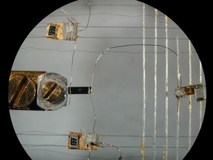 This microscope image shows thermometers (top and bottom) and a heater (right) connected via 50-micrometer-wide gold wires to a black rectangle of the ytterbium dirhodium disilicide (center) that is only three-quarters of a millimeter wide. Using this setup, researchers at the Max Planck Institute for Chemical Physics of Solids in Dresden, Germany, induced a thermal current by setting up a small difference in temperature at the two ends of the sample. The proportionality coefficient between this temperature difference and the thermal power provided by the heater defined the thermal conductivity of the sample, which was found to violate traditional laws of physics when the material was cooled to a "quantum critical point."
CREDIT: Heike Pfau/Max Planck Institute, Dresden