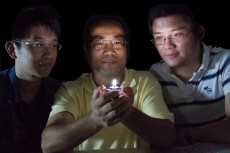 The University of Georgia's Zhengwei Pan, center, an associate professor of physics and engineering, holds a prototype of what is thought to be the world's first single-phosphor, single-emitting-center-converted LED that emits a warm white light while the UGA College of Engineering's Feng Liu, left, and Xufan Li look on.