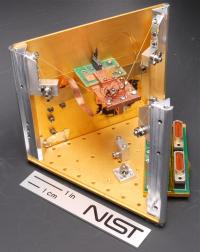 NIST's prototype solid-state refrigerator uses quantum physics in the square chip mounted on the green circuit board to cool the much larger copper platform (in the middle of the photo) below standard cryogenic temperatures. Other objects can also be attached to the platform for cooling.

Credit: Schmidt/NIST