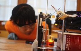 A middle-school student at the Next Generation School in Champaign, Ill., creates a 3-D object with a classroom 3-D printer. Students in grades K-12 can "print" 3-D objects from computer-generated sources right in the classroom using a rapid prototyping or 3-D lithography process. The process is based on a research project that was headed by Nicholas Fang, an assistant professor in the Mechanical Engineering Lab at the University of Illinois at Urbana-Champaign and developed at the Center for Nanoscale Chemical-Electrical-Mechanical Manufacturing Systems (NanoCEMMS) at the university. NanoCemms is a National Science Foundation Nanoscale Science and Engineering Center. 
The process uses UV sensitive monomer to do a form of 3-D printing called microstereo lithography. The students use a video projector with a UV output to create incredibly thin polymer layers (on the order of 400 nanometers) and build objects layer by layer. The activity demonstrates the basic challenges of nanoscale engineering. 
The 3-D printing process has already been used by hundreds of students in Illinois at all grade levels to turn mathematical models into objects that they can touch and feel. 
Nano-CEMMS provides a wide range of human resource development activities targeted toward increasing both the diversity of students involved with the center and educational opportunities at the K-12 and undergraduate levels, as well as providing graduate students with teaching experience in an emerging field. To learn more about the center, visit the Nano-CEMMS website. [Research supported by NSF grant CMMI 07-49028, awarded to John Rogers. Date of project shown in image: 2008-2010]

Credit: Joe Muskin, University of Illinois