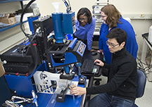 Tahira Reid, at left, and Amy Marconnet, both assistant professors of mechanical engineering at Purdue University, work with graduate student Jaesik Hahn in using an infrared microscope to study how heat affects hair. Hair is studied while heat is applied with a flat iron. The goal is to learn precisely how much heat to apply in hair styling and how frequently to use heat treatment for a given hair type without destroying it. Purdue University image/Mark Simons